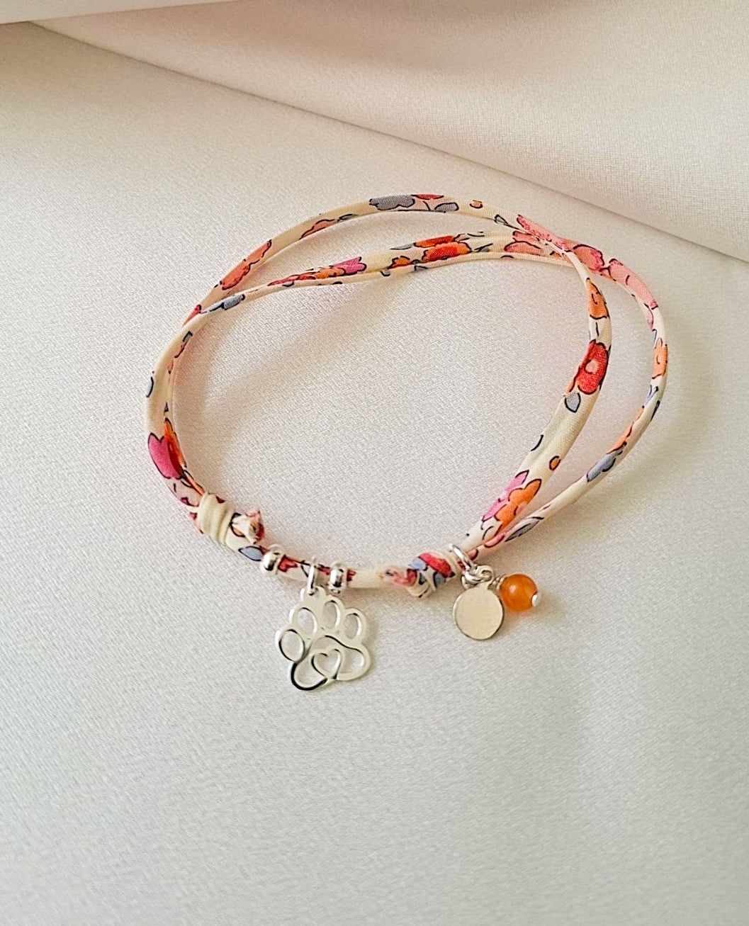 pulsera artesanal, de tela liberty floral con dije de huella de plata.